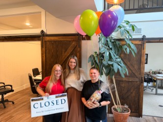 Clients celebrating with a Closed sign and balloons