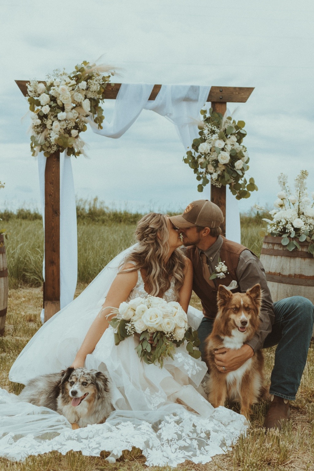 Jordan and Derek on their wedding day with their two dogs in the pasture of Jordan’s childhood home